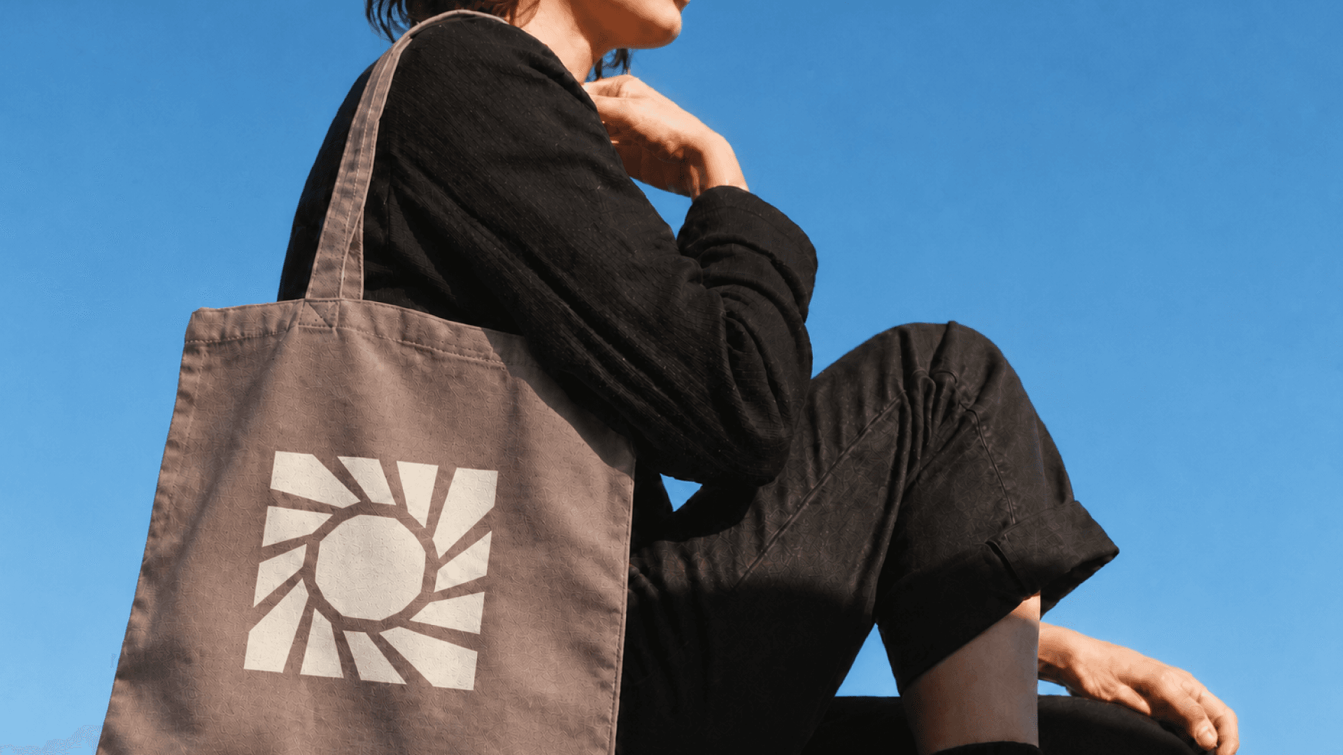 ARTISUN sun identity printed on a tote bag against a blue sky